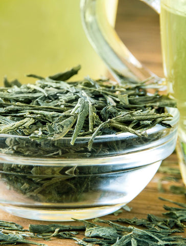 Glass bowl filled with green tea leaves