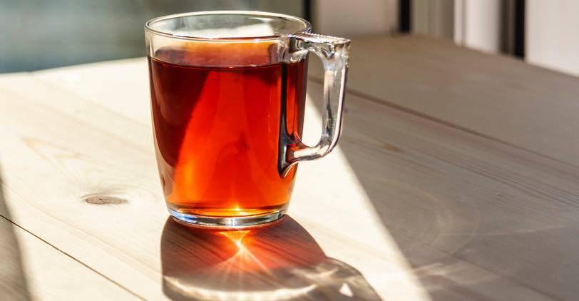 A glass cup of brewed English Breakfast tea in the morning light
