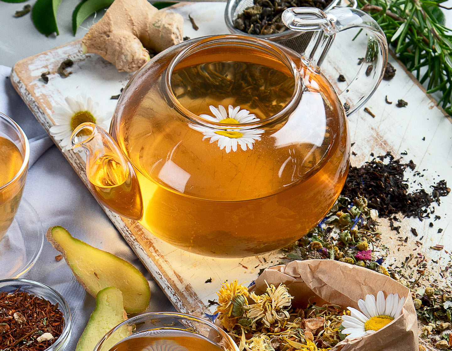 Herbal tea in a glass teapot with herbs all around