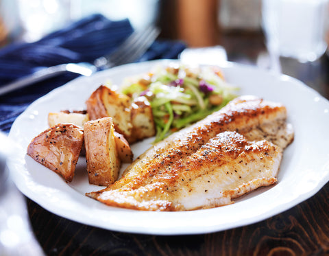 Cooked fish and potatoes on a white plate