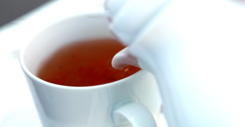 Pouring black tea into a white cup