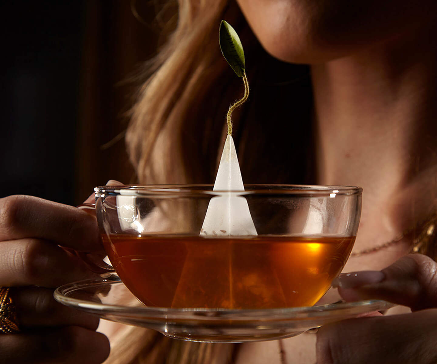 Woman holding a glass cup steeping tea with a pyramid tea infuser