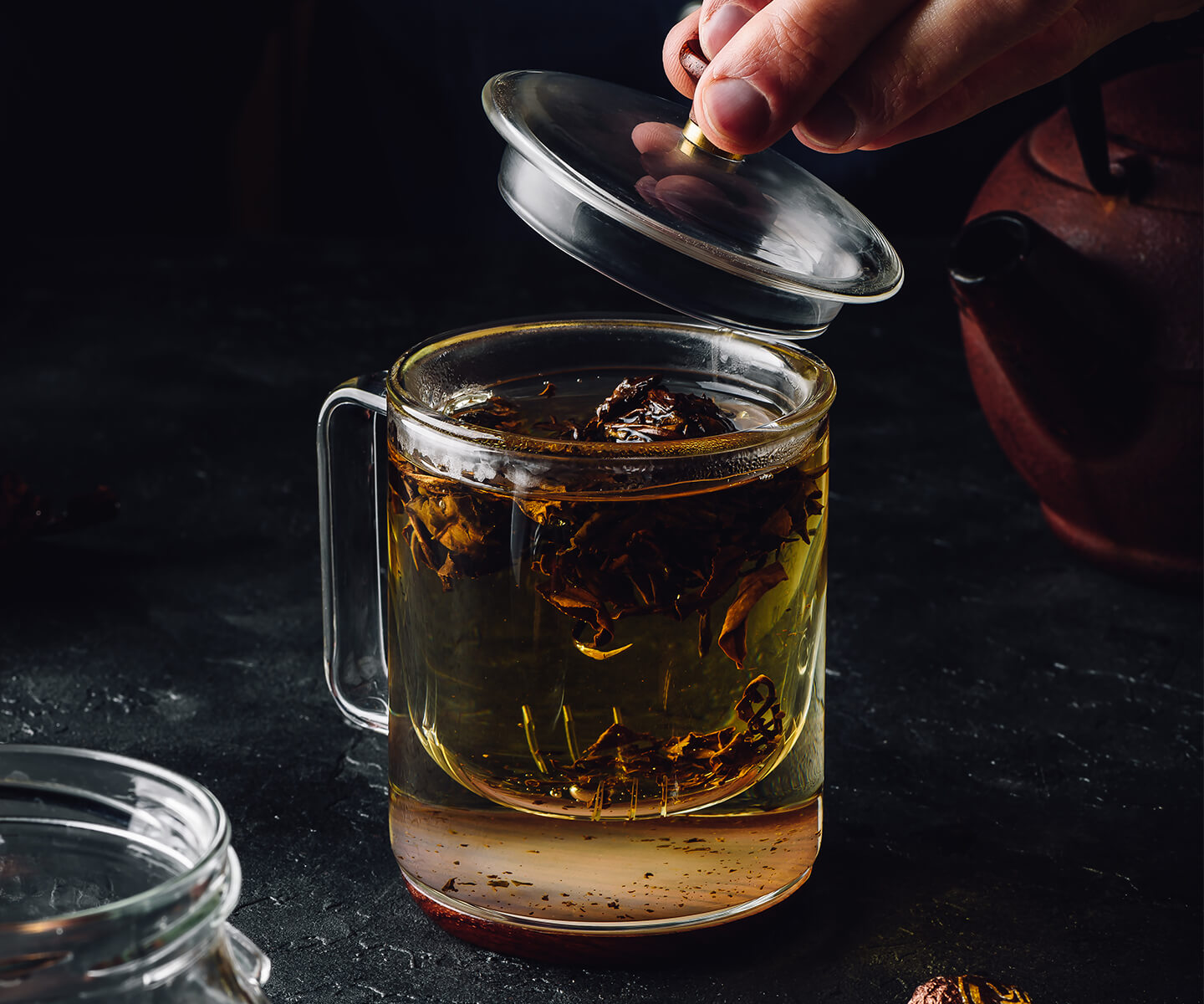 Man stteping a cup of oolong loose leaf tea in a glass mug