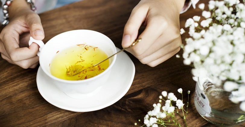 Herbal tea in a white cup and saucer on a wooden table