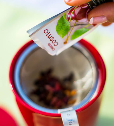 Pouring a pouch of cherry tea into a red KATI steeping cup