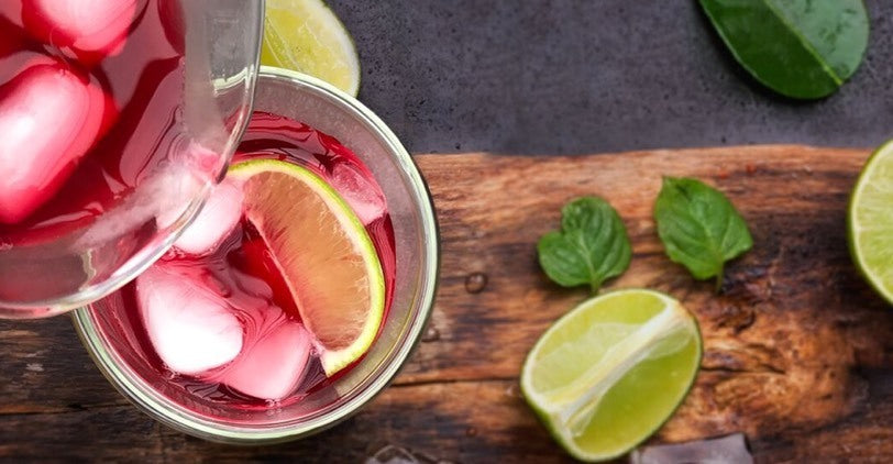 Glasses of Raspberry Nectar iced tea on a wooden tray with limes