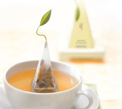 White cup with a pyramid tea infuser steeping