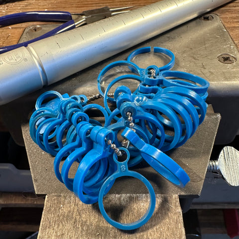 a set of blue plastic ring sizers sits on a jewelers bench with a ring sizing mandrel in the background.