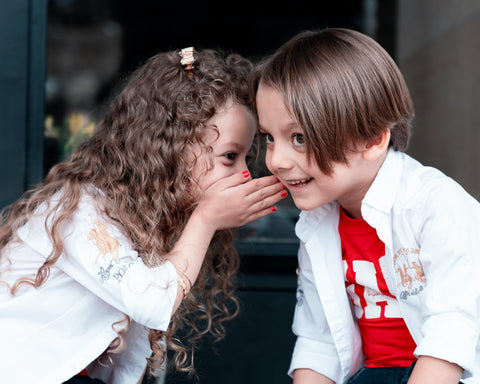 2 children appearing to share a secret with each other
