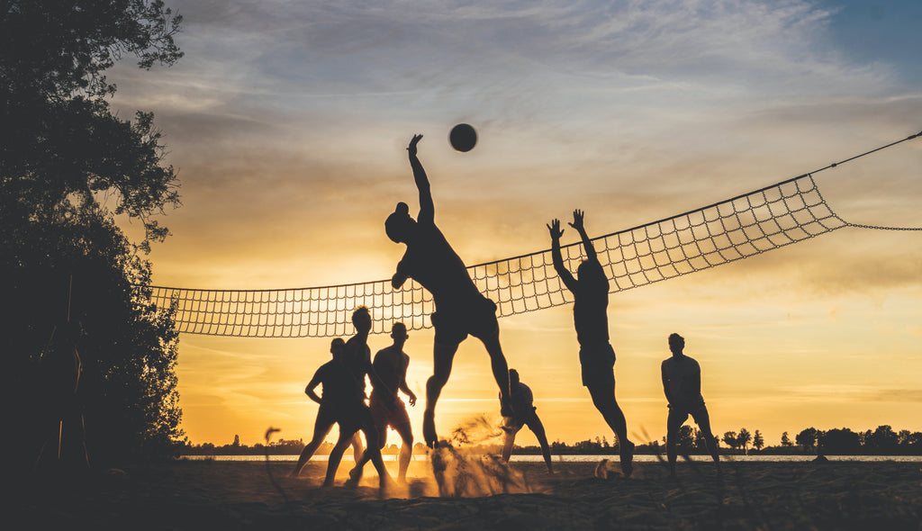groupe de personnes jouant au volley au coucher du soleil 