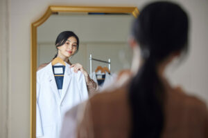 白衣を鏡で当てる女性