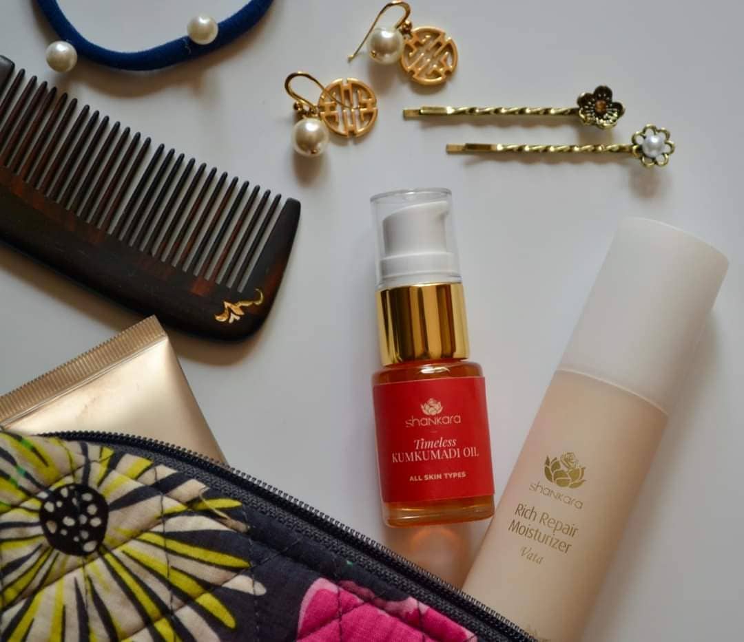 A bottle of Shankara's Rich repair serum next to kumkumadi oil bottle, surrounded by jewellery and make up.