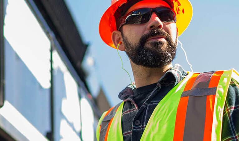 Worker wearing a high visibility vest and hard hat.