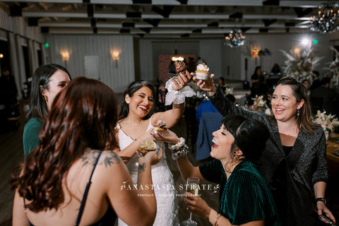 Bridal party cheers-ing with cupcakes to celebrate wedding