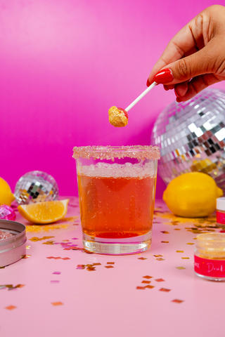 Woman dips lollipop into drink glitter and then into disco lemonade drink