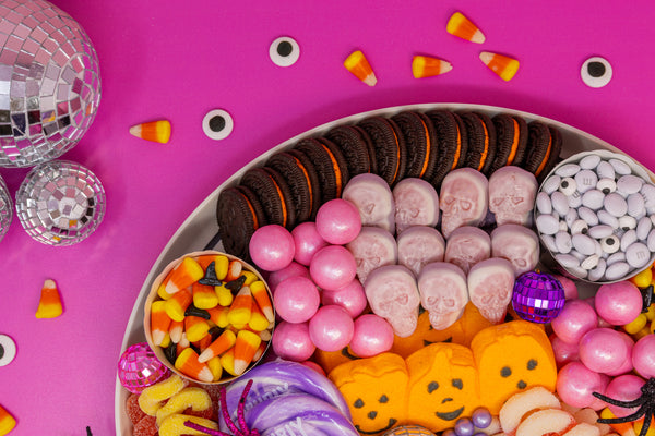 Edge of Pink Disco Halloween Candy Charcuterie Board, showing Oreos, Gummy Skulls, Gumballs, Candy Corn, and a variety of other candies.