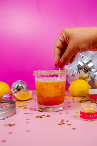 Woman dips drink glitter lollipop into a disco lemonade drink