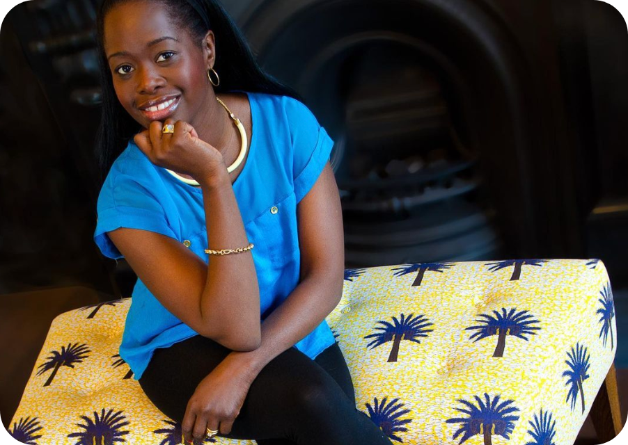 Portrait of Eva Sonaike sitting on a yellow pillow with blue palm tree pattern