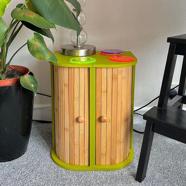 IKEA bread bin hack presented by two bread bins put together as a sideboard and painted with YesColours Passionate Olive Green paint colour, photographed next to a large plant