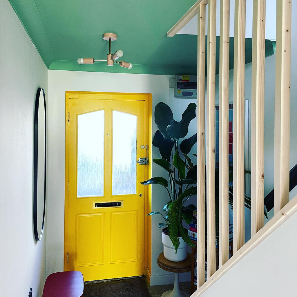 Airy and bright hallway with a stairwell, mirror on the wall, a green ceiling and a yellow front door