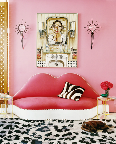 Salvador Dali's Mae West Lips sofa in red, photographed in front of a pastel pink painted wall and placed on a white and grey leopard print large carpet