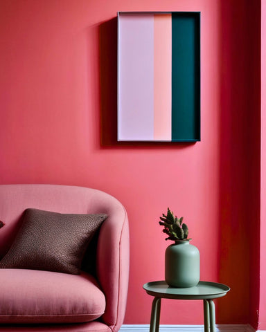 pink coral watermelon coloured walls in a living room, with a coral coloured abstract art print on the wall and a pink sofa and a teal green vase and side table underneath