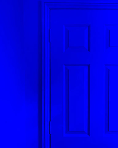 close up of a wall and a wooden door all painted in the same ultramarine blue colour