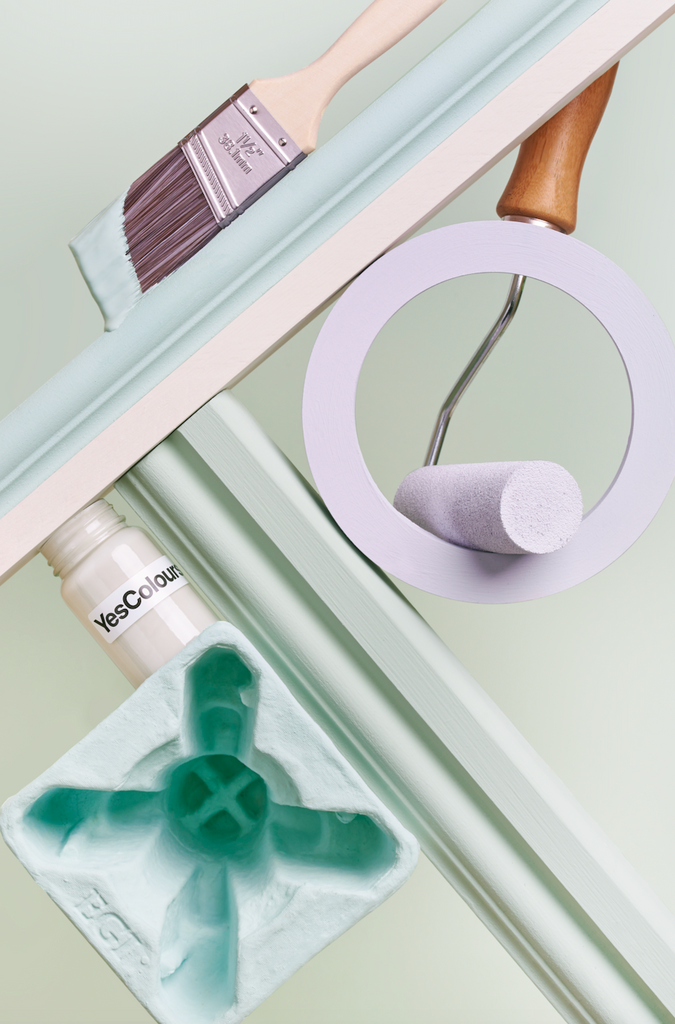 A selection of paint and DIY accessories, such as small paint roller, pulp packaging, wooden coving samples and paint brush photographed on a light green background