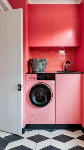 utility room photo with cupboards, tiles and washing machine coloured in a warm coral watermelon shade and geometric shaped black and white floor tiles on the floor