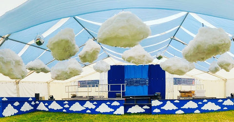 A wide landscape image of a sheltered bar stage area with the bar painted in a dark blue colour with white clouds all over it, a big dark blue stage behind the bar and floating clouds spread evenly within the space