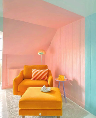 corner of a snug room with vintage mustard yellow sofa chair and ottoman and split coloured wall in pastel peach and mint aqua green