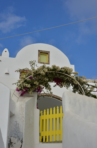 White Island aesthetic stone building with bright yellow wooden gate photographed in front of a bright blue sky