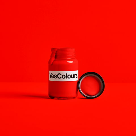 Photo of a little jar with a sticker saying 'YesColours' filled with bright red paint and with its lid placed next to it, all photographed on a bright red background