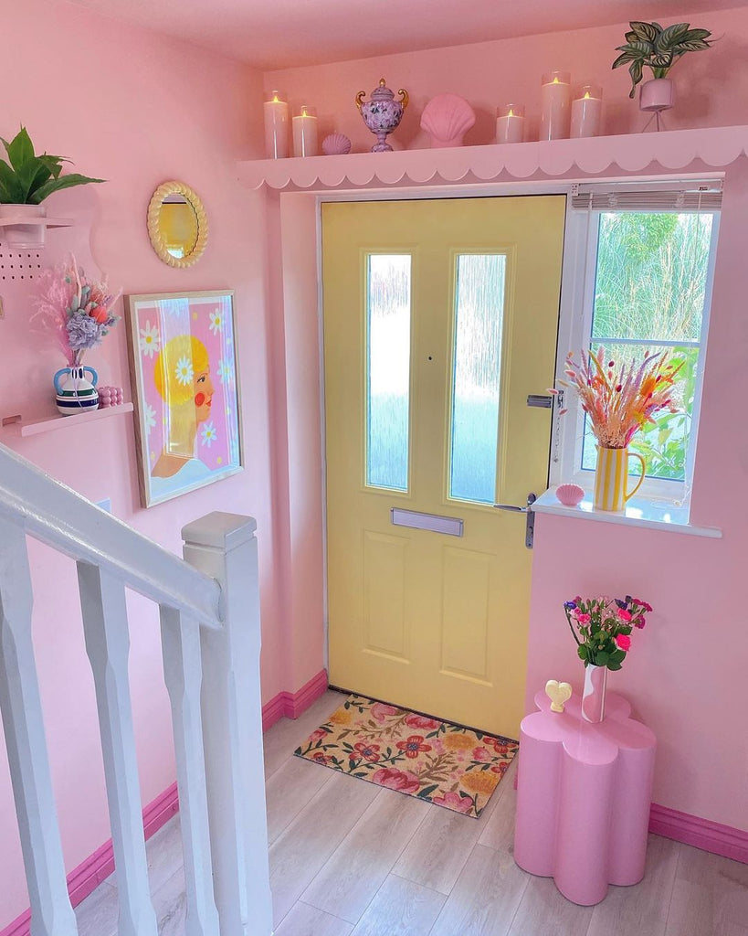 Bright pink hallway with pink walls, pink stool and a pastel yellow front door