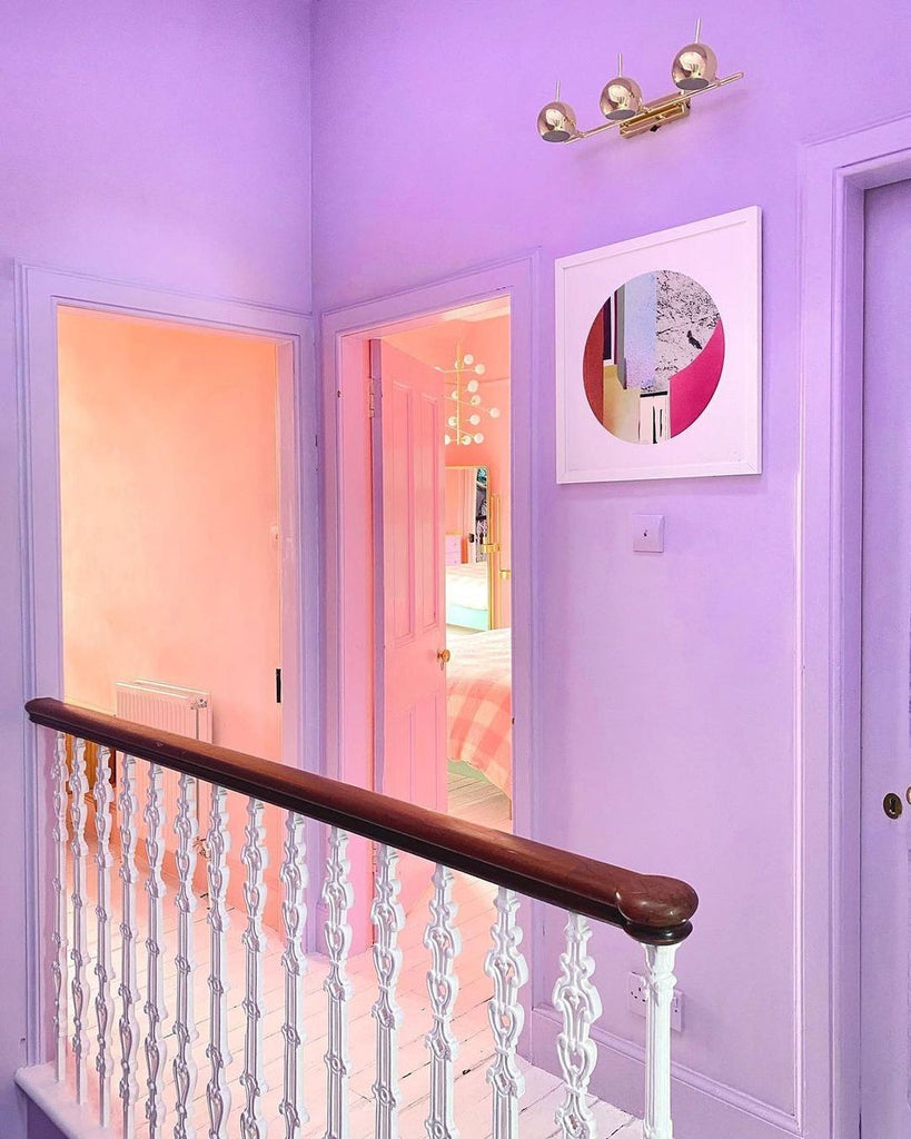 top floor hallway painted in a pastel lilac colour, with an open door to another room painted in a peach colour