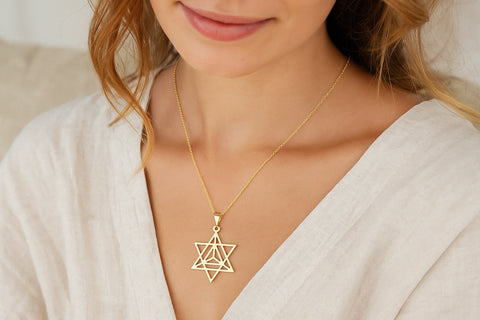 Femme portant un collier Merkaba doré sur une blouse claire, symbole d’harmonie et de spiritualité