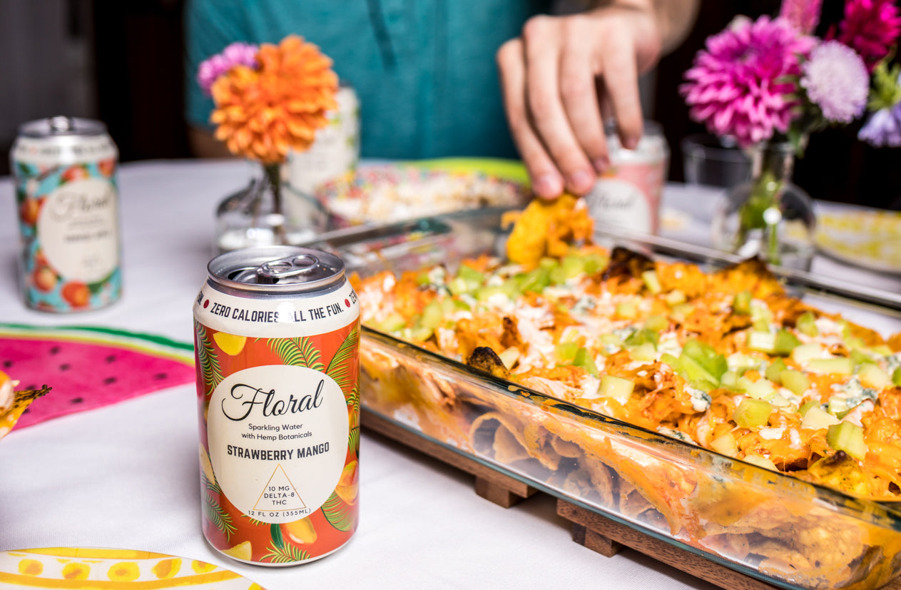 A can of Floral Beverages Strawberry Mango THC Seltzer beside a platter of taco dip.