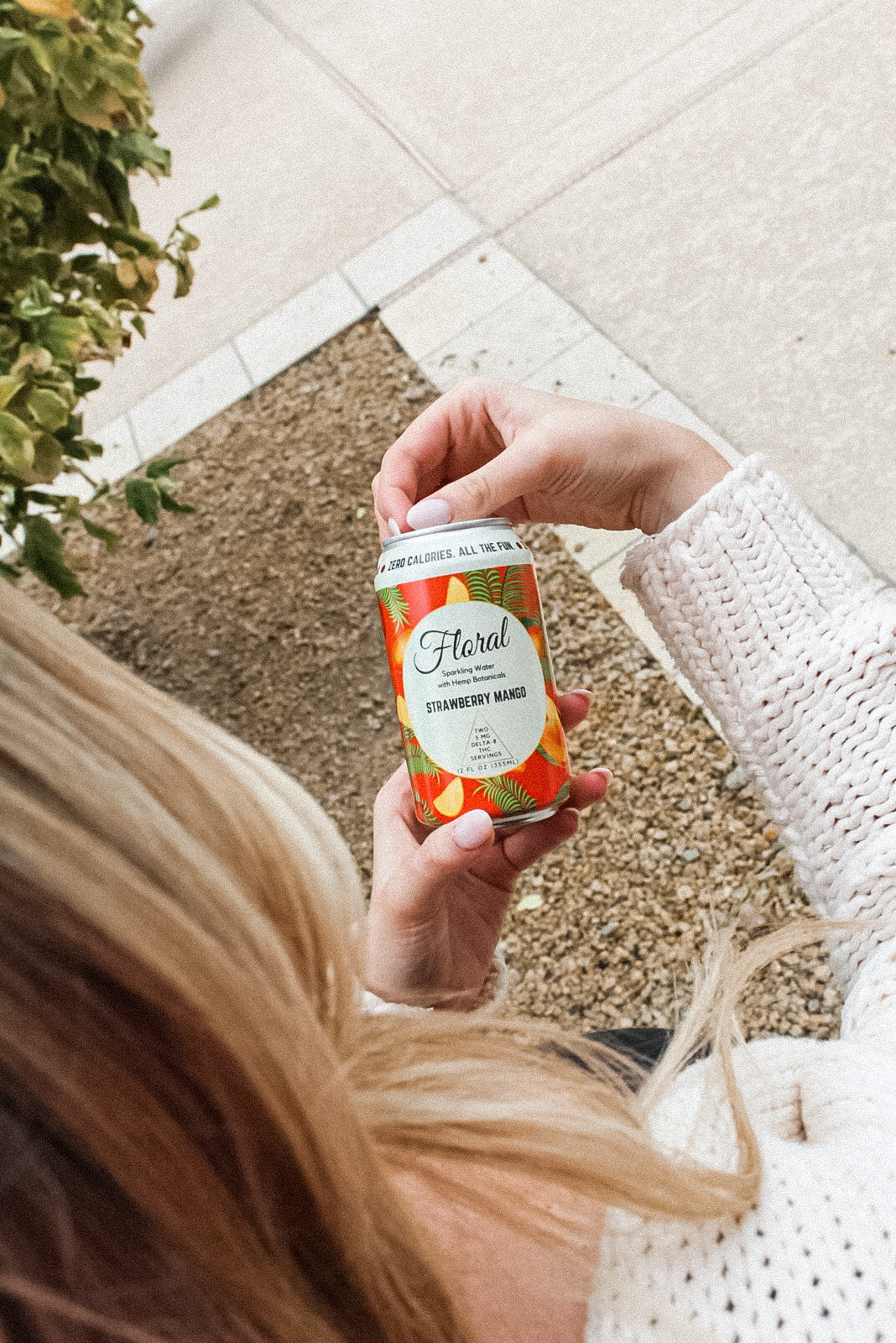 A woman holding a can of Floral Beverages Strawberry Mango THC-infused seltzer.