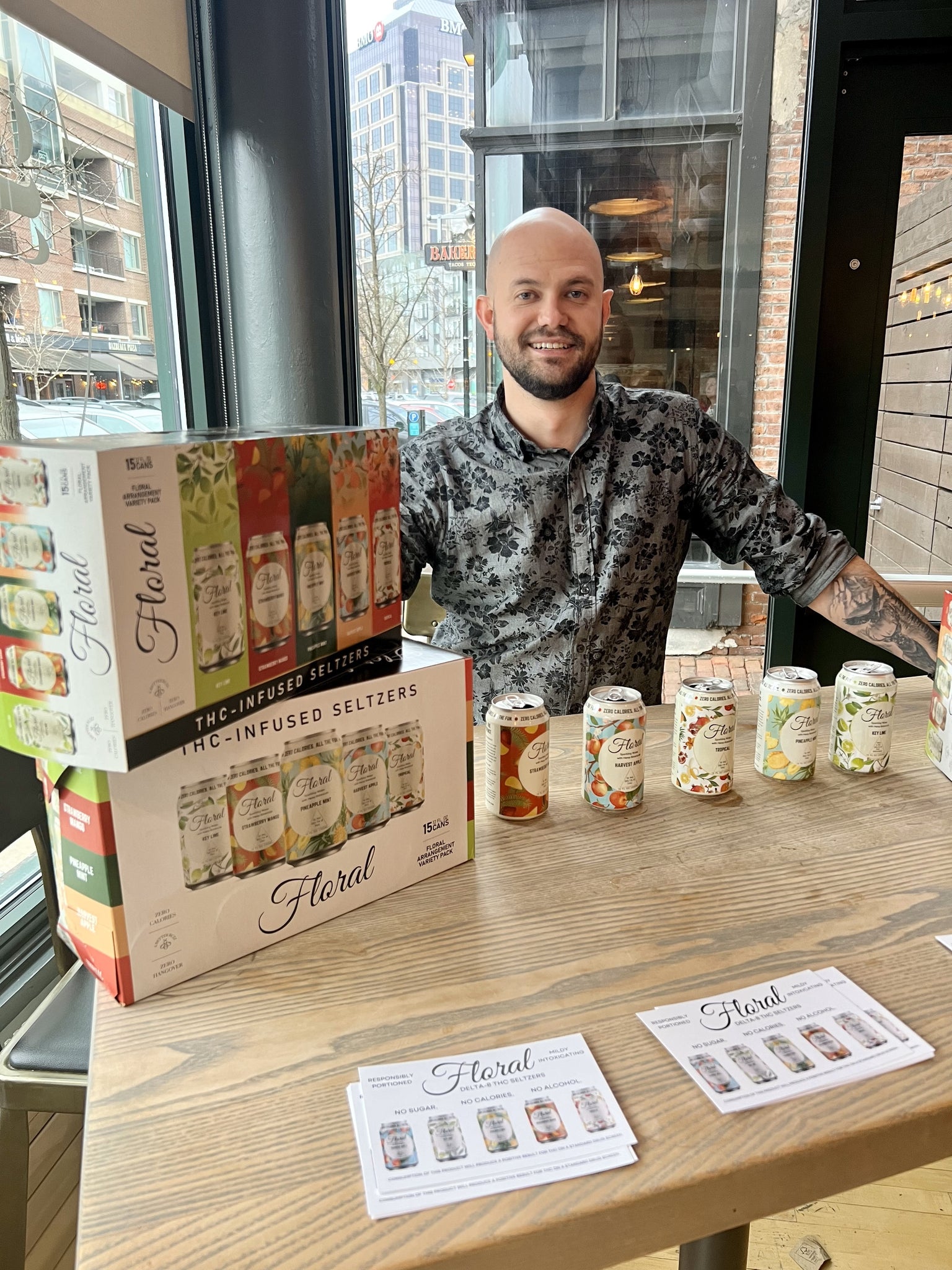 Man standing at a table with Floral Beverage's THC-infused seltzers sitting on the table.