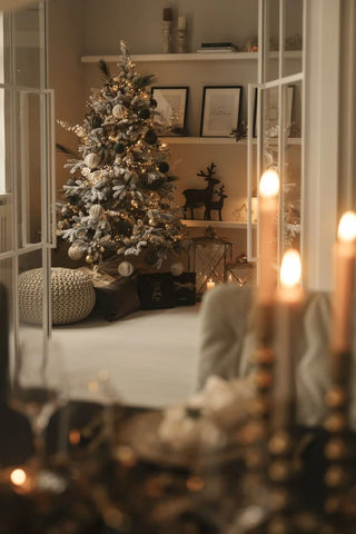 Künstlicher Weihnachtsbaum mit Schnee, kerzen im Vordergrund, golden weiße Dekoration am Weihnachtsbaum warmes licht