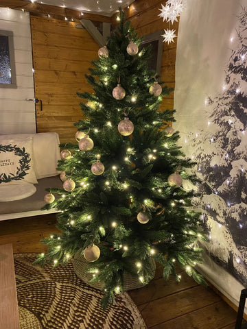 Künstlicher Weihnachtsbaum wie echt in einem Raum mit Beleuchtung und Schmuck