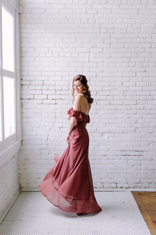 bridesmaid in scarlet ruffle dress twirl in front of white brick wall