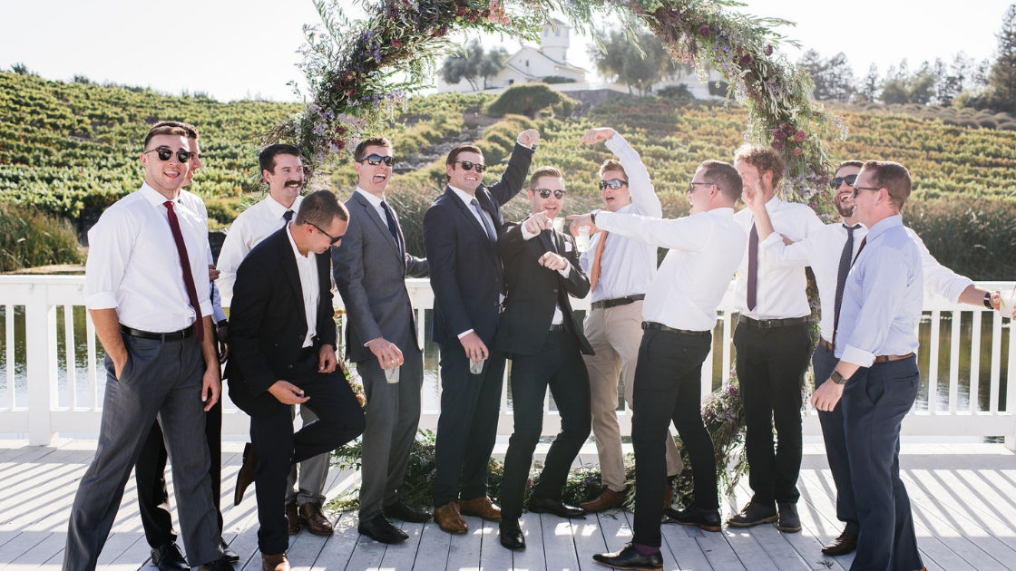 Groom and groomsmen smiling and laughing celebrating on wedding day with their best friends love friendship