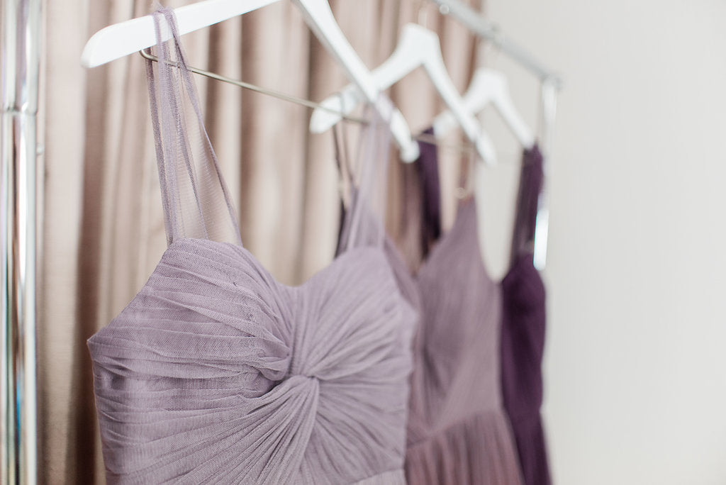 Purple revelry dresses in tulle hanging up on wall with beautiful details