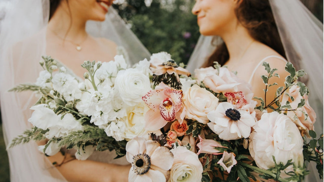 Two brides wedding dresses veils flowers florals white pink blue flowers lesbian wedding lgbtq