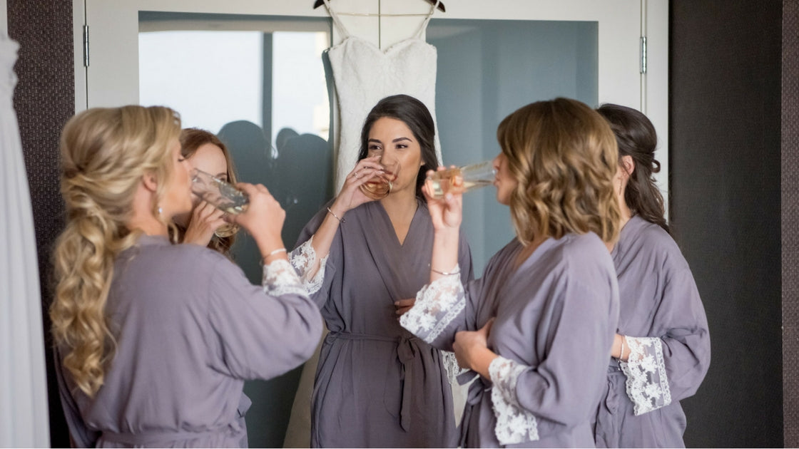 bridesmaids sipping on champagne in matching mauve lace lined roves while getting ready for the Las Vegas Wedding.