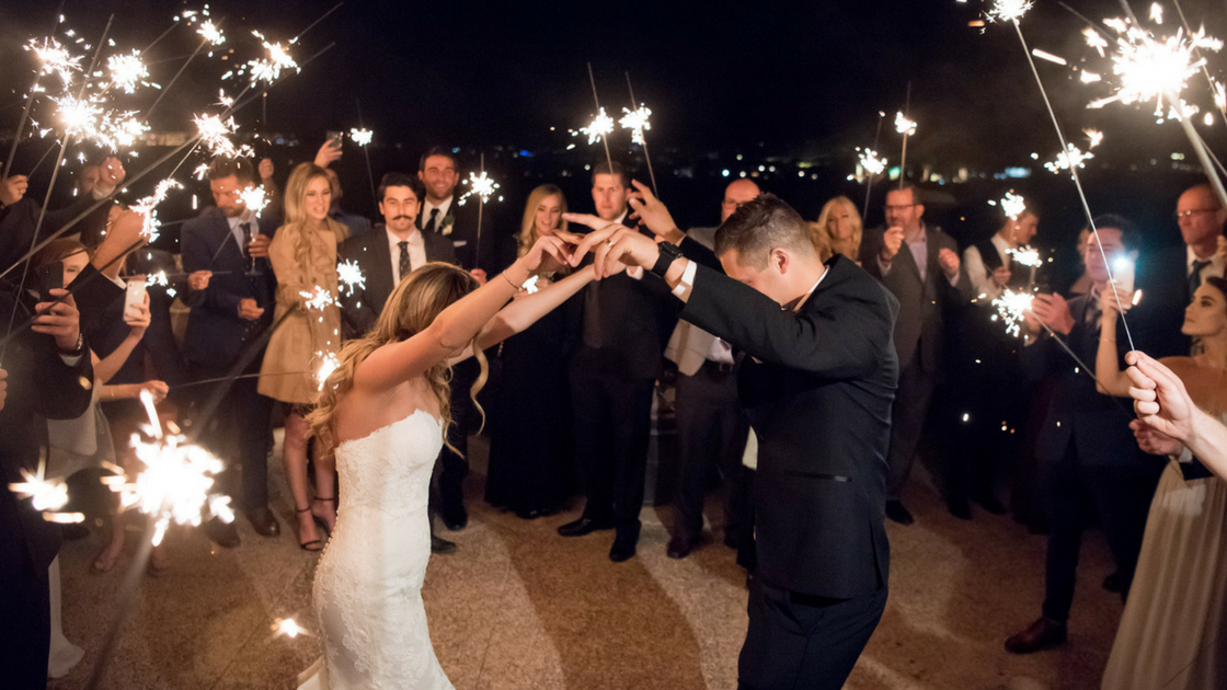 bride and groom dance under sparklers on their way out of the reception and on to their honeymoon.