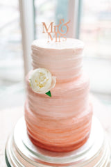Peach pink three tier wedding cake with one white flower