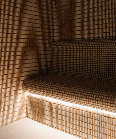 Tiled sauna room at Ember Bathhouse, echoing the aesthetics of a traditional Moroccan hammam with warm, intricately designed tiles creating an ambiance of relaxation and warmth.