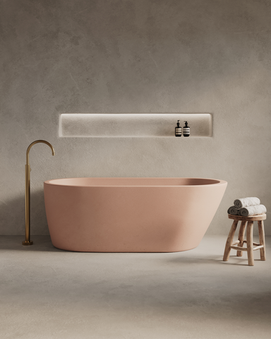 Juno Concrete Bathtub in Blush Pink finish in a moody setting with rendered walls and archway.